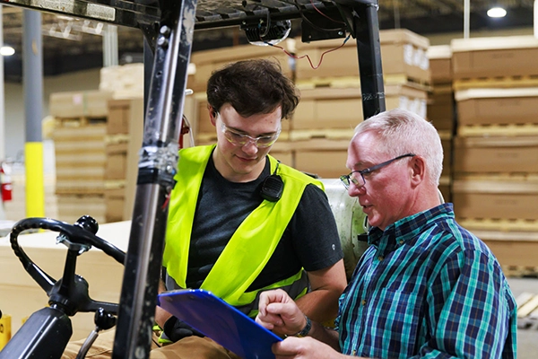 Trimac worker with clipboard talking to guy in neon vest