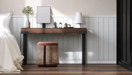 A bedroom vanity sits in a bedroom against a beige wall with white beadboard wainscoting.